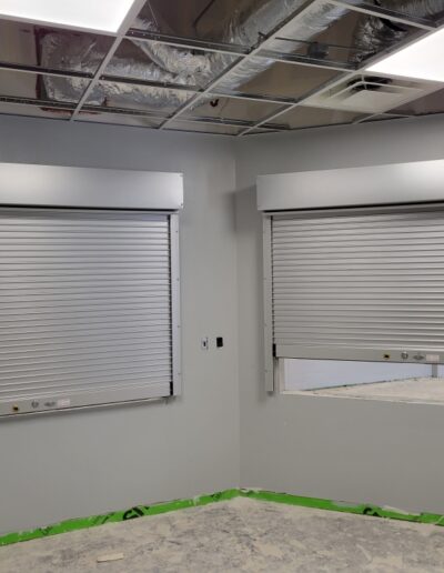 A room featuring two roller shutters and a window, showcasing a blend of functionality and natural light.