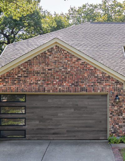 A sturdy brick house with a well-defined garage door, exemplifying traditional residential design and durability.