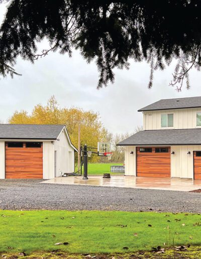 A large house featuring two garages and a spacious driveway, showcasing a well-maintained exterior.