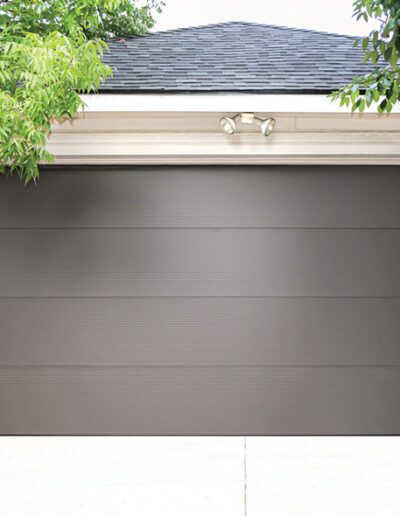 A gray garage door is framed by a vibrant tree, enhancing the peaceful ambiance of the setting.