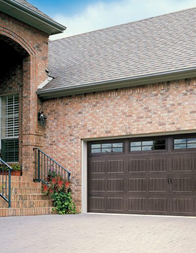 A brick house featuring a prominent garage door, showcasing a classic architectural style and sturdy construction.